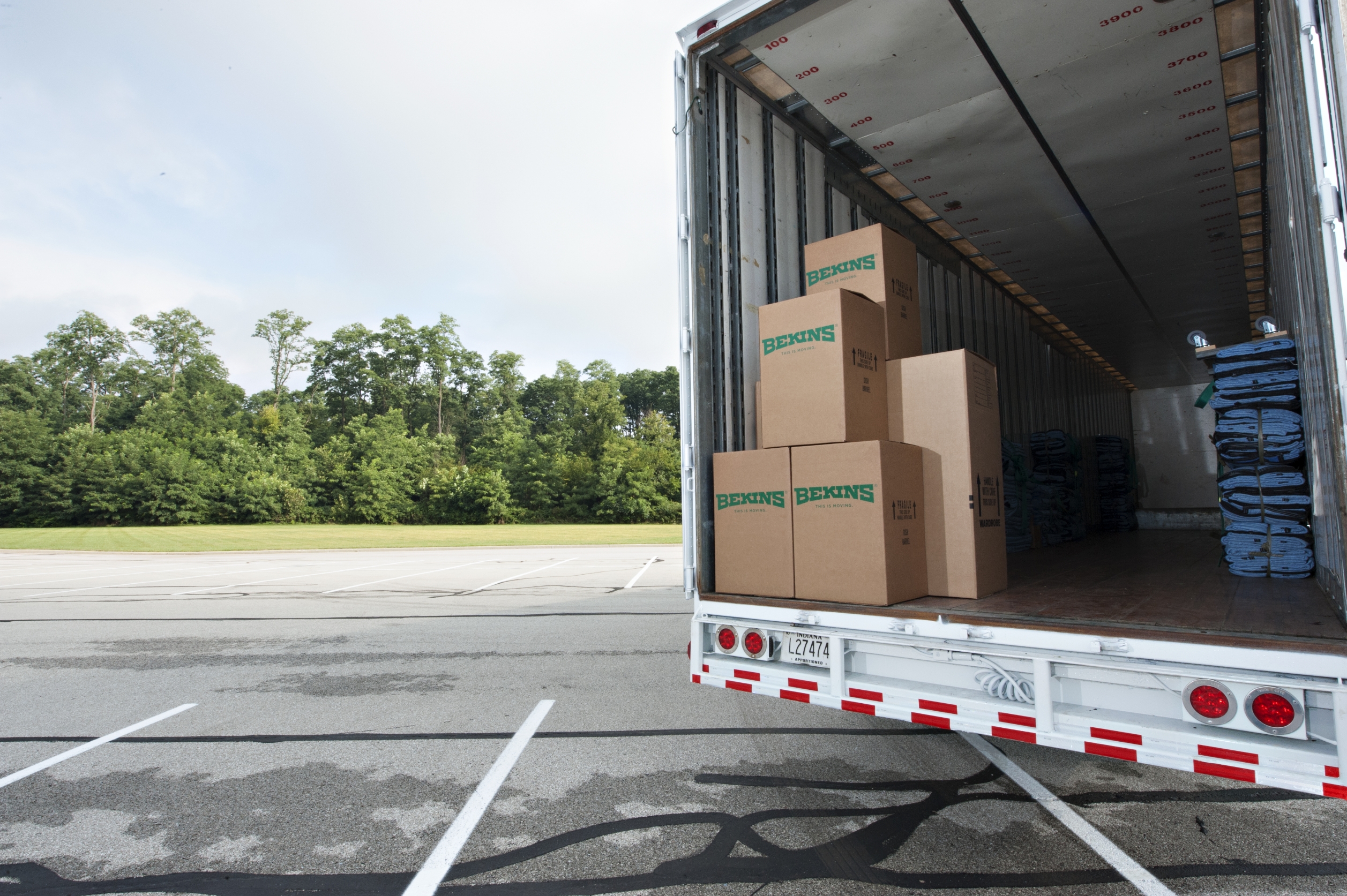 A Bekins Moving Truck With The Back Open, Showing Cardboard Boxes Inside