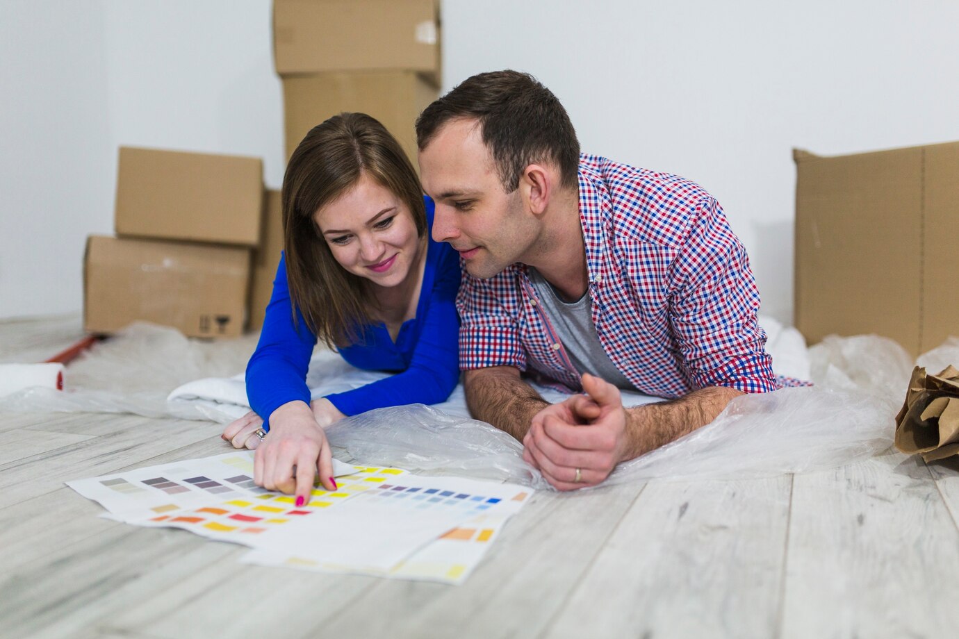 Two People Examining Color Swatches On The Floor With Moving Boxes Around